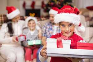 Festive daughter holding pile of gifts with his family behind