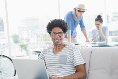 Young creative man using laptop on couch