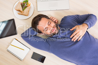 Happy man lying on floor surrounded by his things