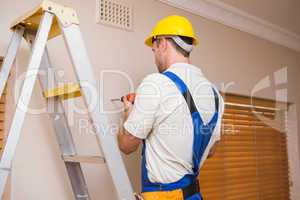 Construction worker drilling hole in wall