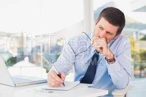Worried businessman writing on is notepad