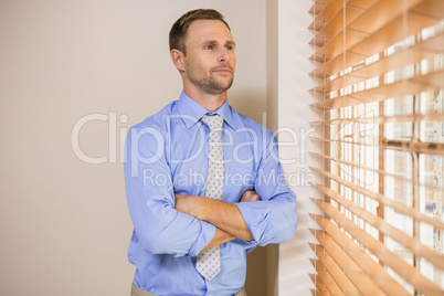 Serious businessman peeking through blinds
