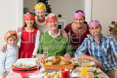 Happy extended family in party hat at dinner table