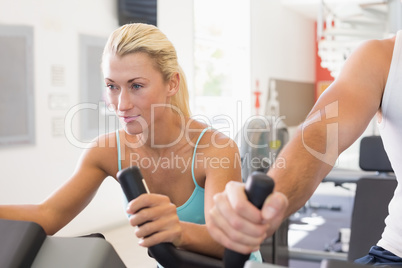 Fit young couple working on exercise bikes at gym