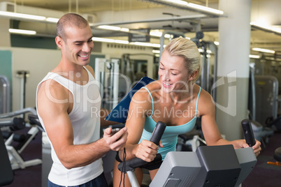 Trainer timing his client on exercise bike at gym