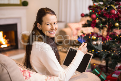 Smiling brunette shopping online with laptop at christmas