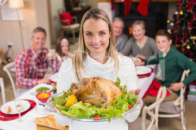 Pretty woman showing the roast turkey in front of her family