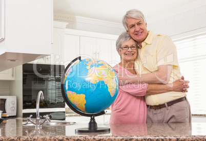Senior couple smiling at the camera together with globe