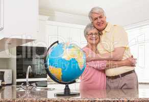 Senior couple smiling at the camera together with globe