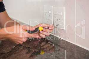 Electrician unscrewing face plate of plug socket