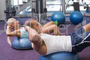 Fit couple doing abdominal crunches at gym