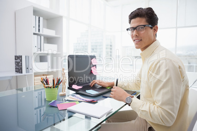 Designer using laptop and smiling at camera
