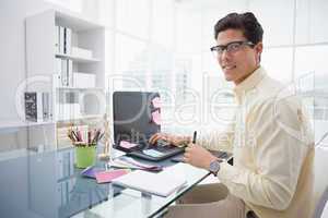 Designer using laptop and smiling at camera