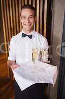 Handsome smiling waiter holding tray of champagne