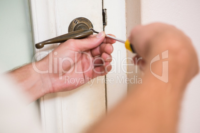 Man fixing the door handle with screwdriver