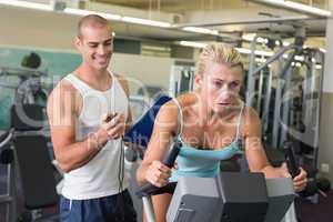 Trainer timing his client on exercise bike at gym