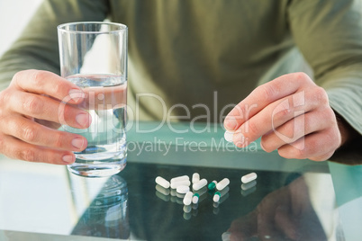 Close up of a man holding pill and glass of water