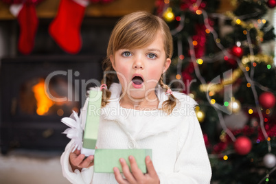 Shocked little girl opening a gift