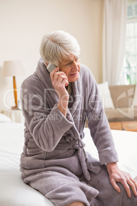 Senior man making a phone call on bed