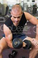 Young man exercising with dumbbell in gym