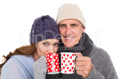 Happy couple in warm clothing holding mugs