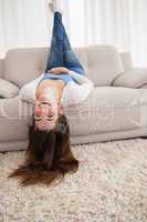 Pretty brunette lying upside down on couch