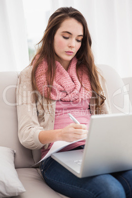 Pretty brunette using laptop on the couch