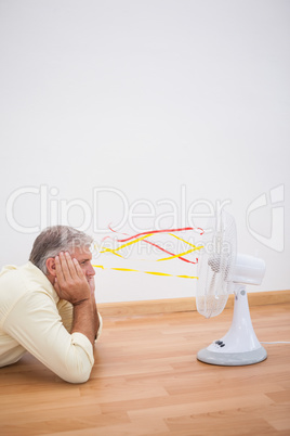 Man lying on floor looking at fan