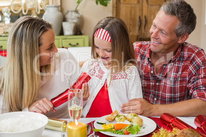 Little girl pulling a christmas cracker with their parents