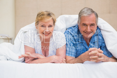 Senior couple smiling under the duvet