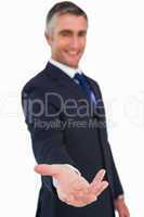 Smiling businessman in suit with arm out