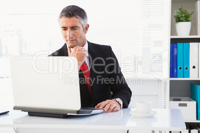 Focused businessman in suit using his laptop