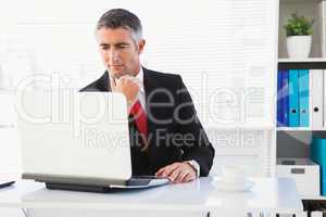 Focused businessman in suit using his laptop