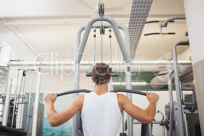 Fit man using weights machine for arms