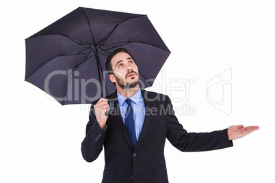 Businesswoman holding umbrella while testing if it rains