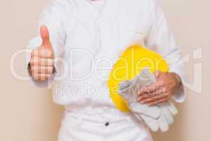 Handyman holding his yellow helmet showing thumbs up