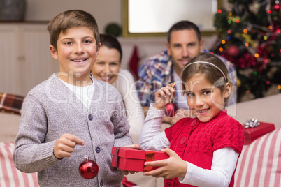 Smiling brother and sister holding gift and baubles