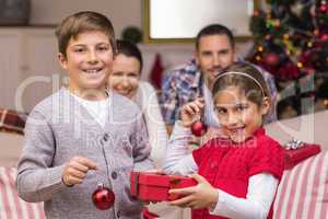 Smiling brother and sister holding gift and baubles