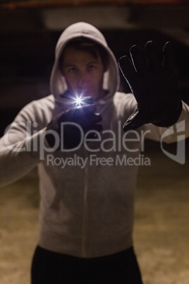 Man in hood jacket standing while making light with his phone