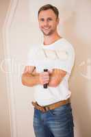 Smiling handyman posing while holding a paintbrush