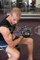 Young man exercising with dumbbell in gym