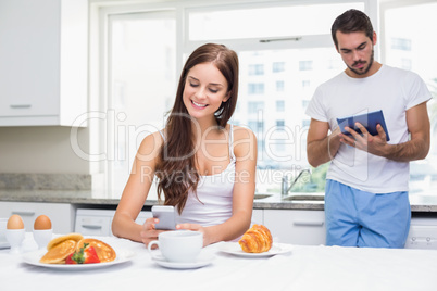 Young couple using technology at breakfast
