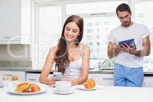 Young couple using technology at breakfast