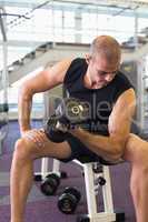 Young man exercising with dumbbell in gym