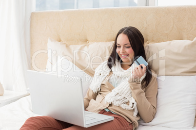 Pretty brunette using laptop on bed