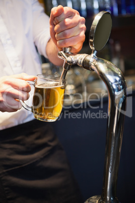 Handsome barkeeper pulling a pint of beer