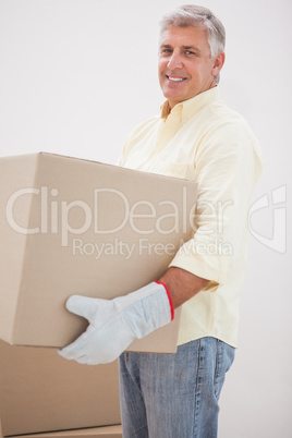 Smiling man carrying cardboard moving boxes