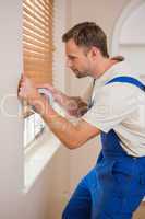 Man puting silver duct tape on the corners of the wall