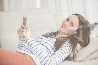 Pretty brunette listening to music on the couch