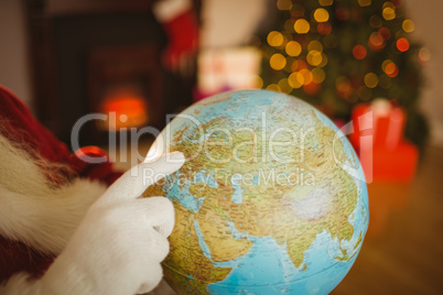 Close up of santa pointing his finger on the globe